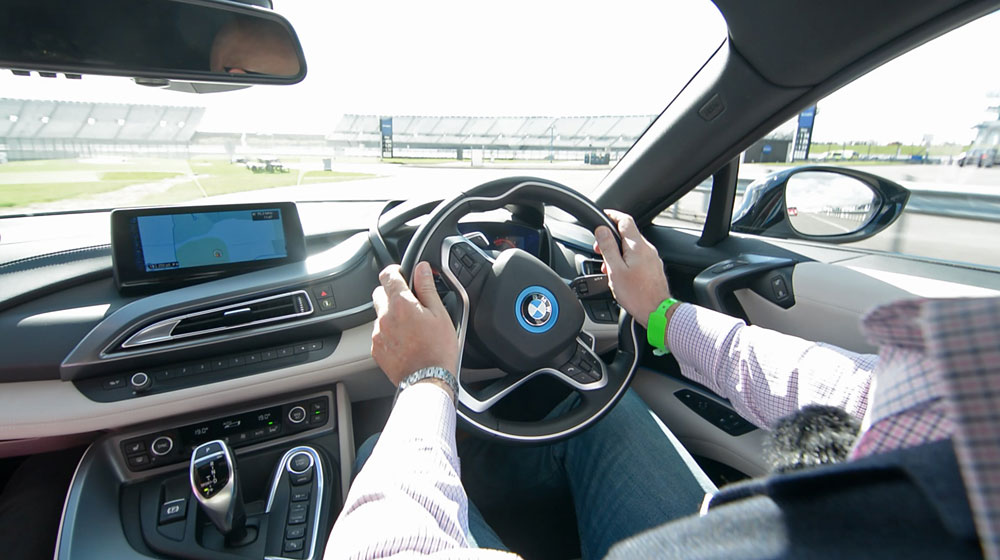 A picture of a man driving a BMW i8.